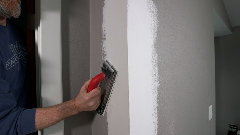 using a hand sander to sand the repaired area